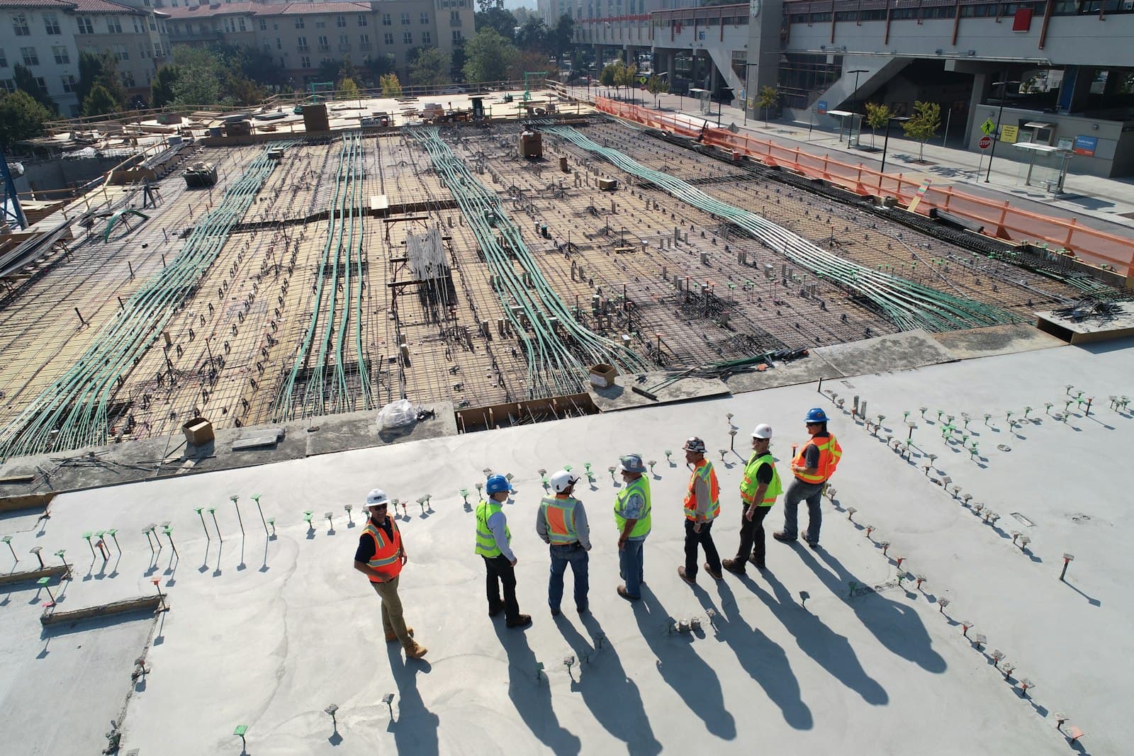 Bauleitung und Team in Warnwesten auf einer Großbaustelle über der Bewehrungsebene